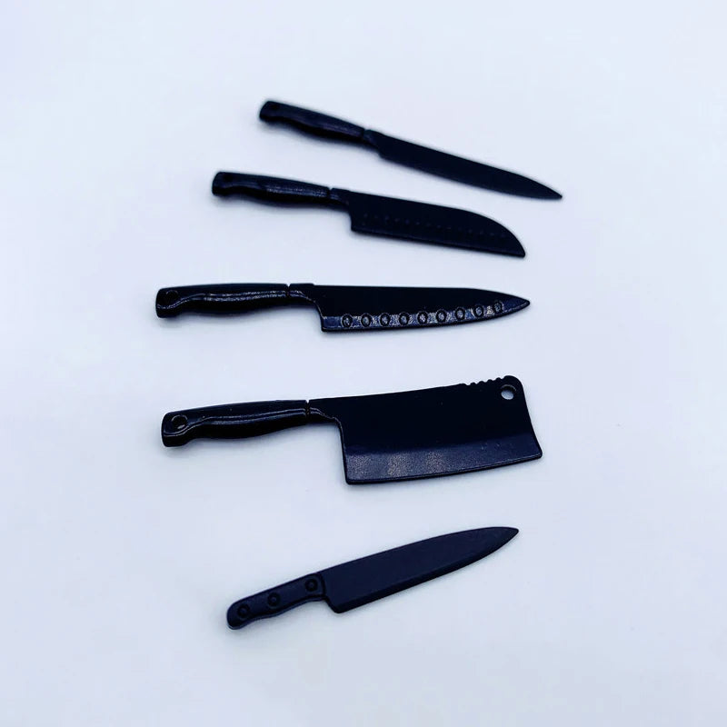 A set of four miniature black metal kitchen knives displayed on a white background.
