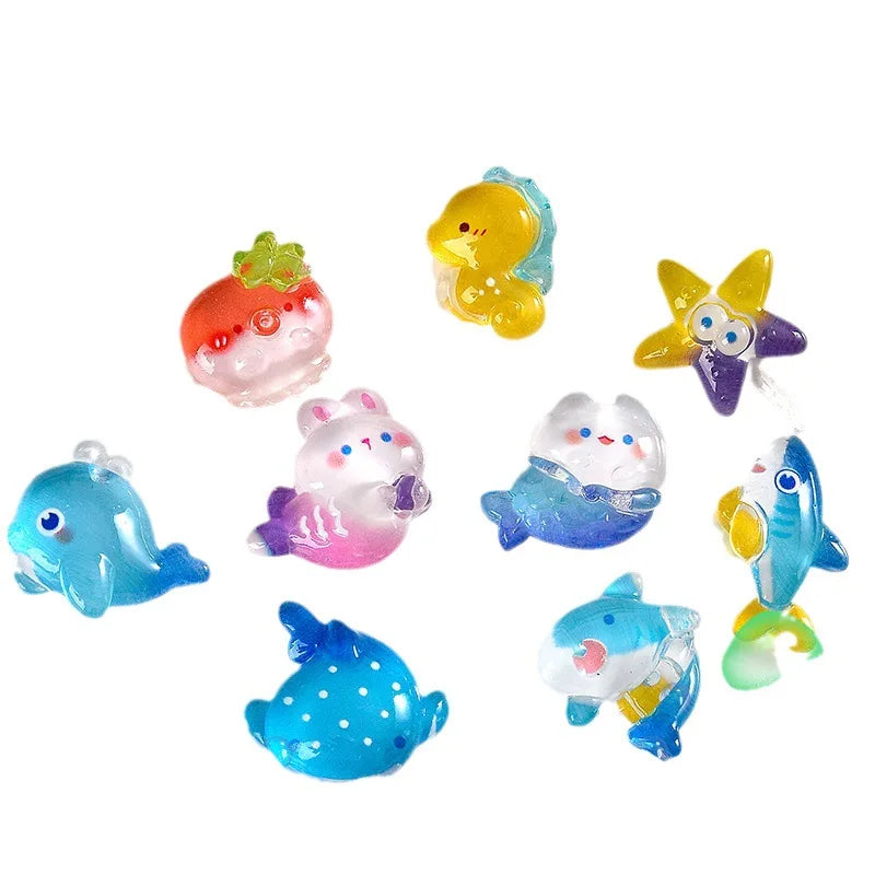 A collection of colorful resin charms shaped like various cute ocean animals including a yellow fish, a pink strawberry, and 