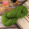 A ball of bright green yarn is shown on a wooden surface next to a color code label.
