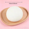 A white squishy bread stress ball resting on a light wooden tray.