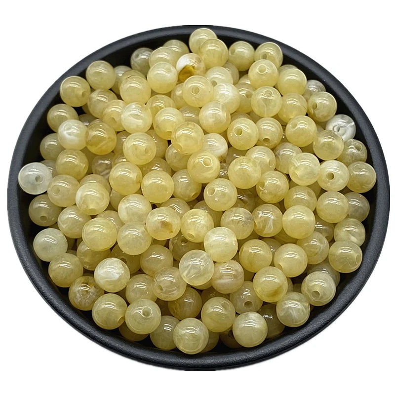 A pile of translucent yellow and clear acrylic round beads for jewelry making.