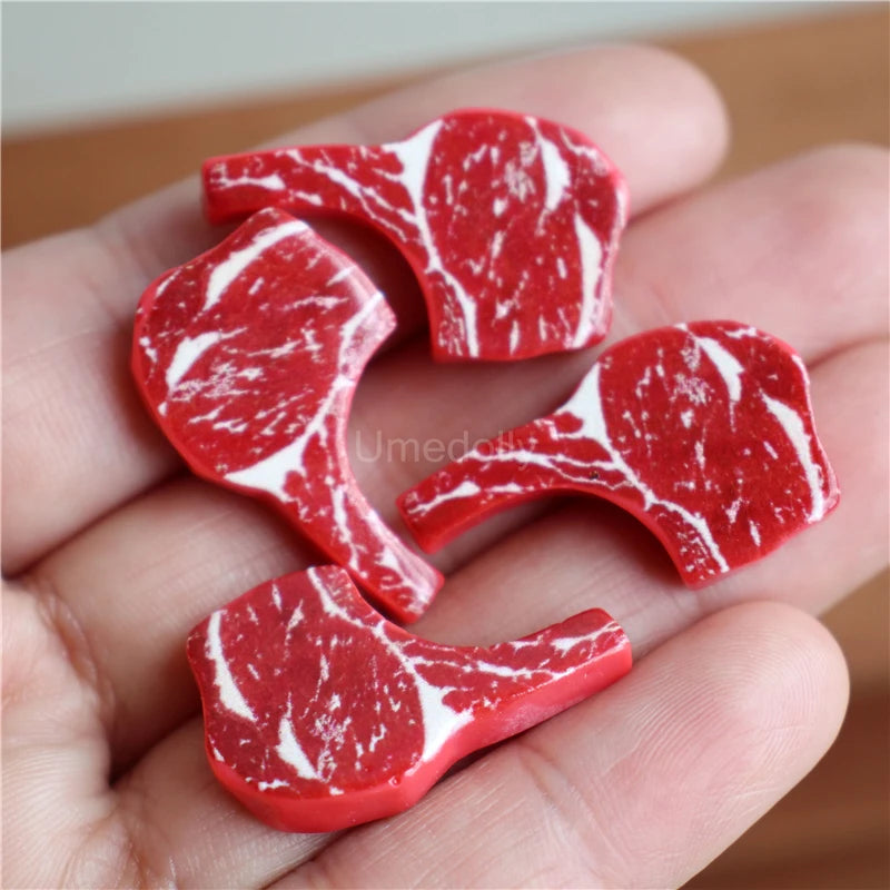 A hand holds several miniature toy food pieces shaped like beef steak and pasta, dyed red and white.