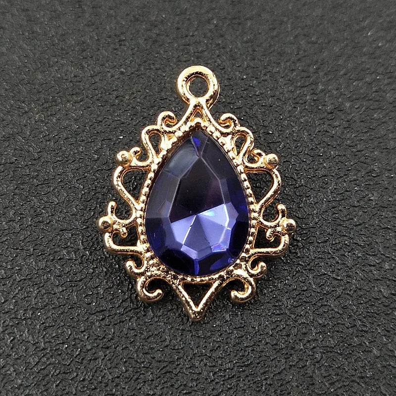 Gold plated water droplet charm featuring a deep blue crystal rhinestone set in an ornate flower design.