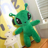 An adorable green alien plush toy with long ears sitting on a wooden surface.