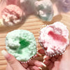 Pink and green squishy stress relief balls are shown in a hand, highlighting their texture and colors.