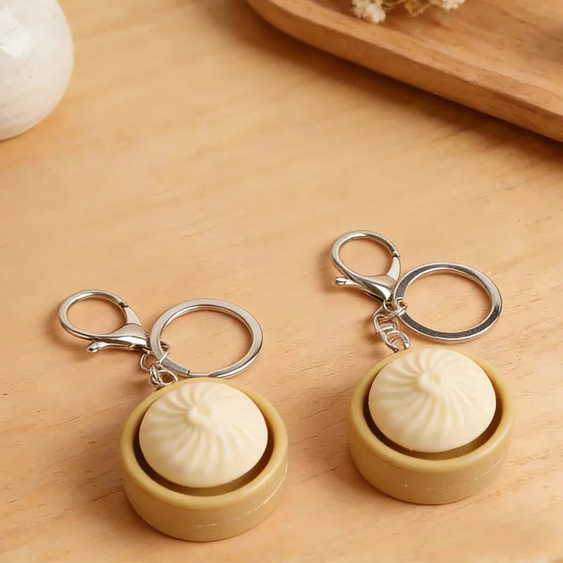 A pair of beige fidget keychains with round white tops resting on a wooden surface.