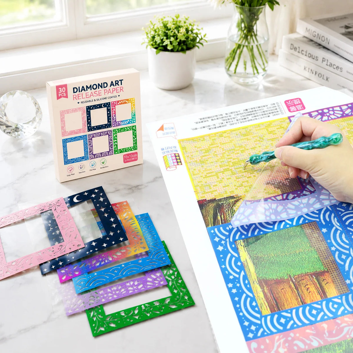 A sheet of diamond art release paper is shown next to a hand applying glue to the paper.