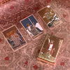A collection of mini gold foil tarot cards, including the Fool, Queen of Swords, King of Pentacles, and other cards, displaye