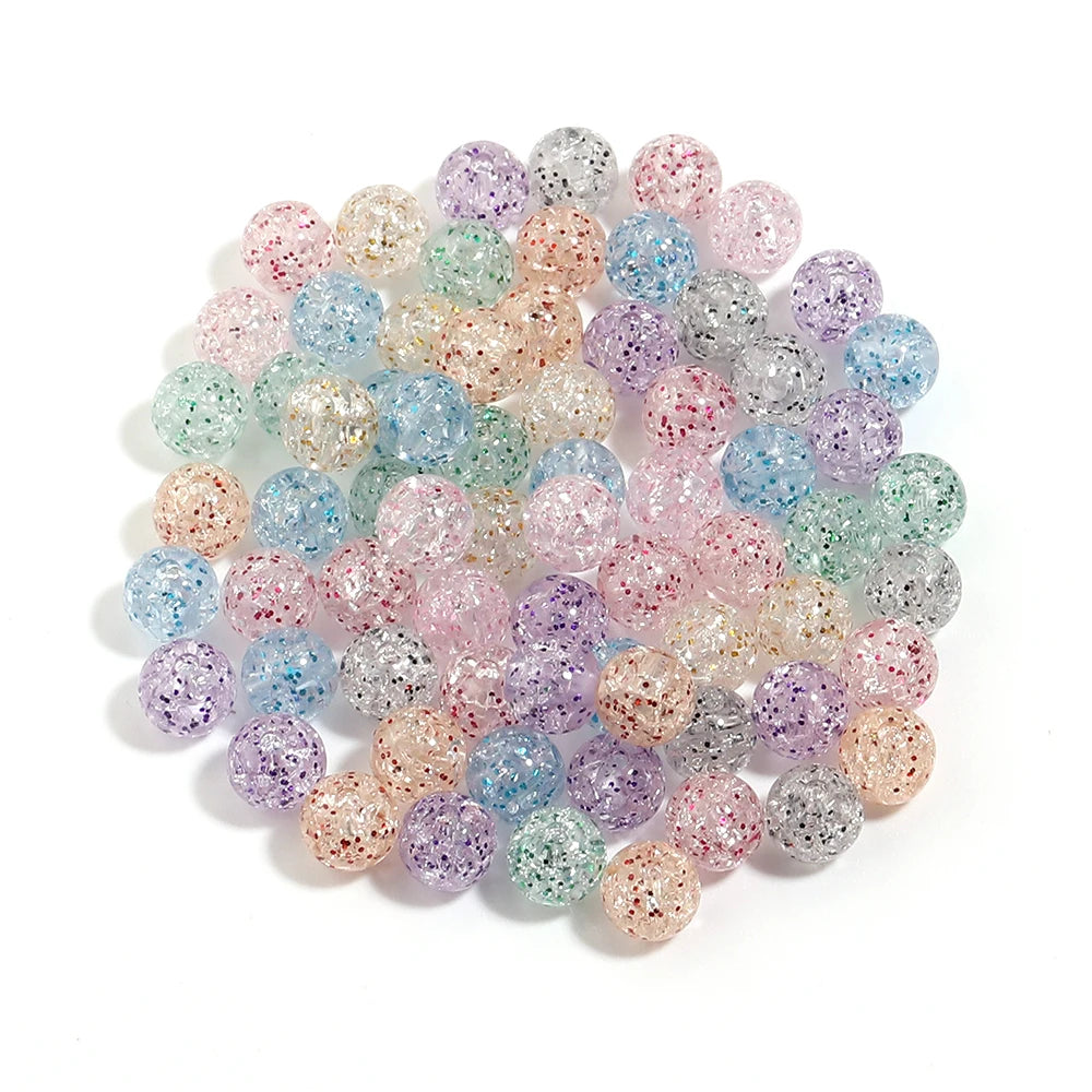 A pile of round loose spacer beads in various shades of glittery pink, purple, blue, and green acrylic for jewelry making