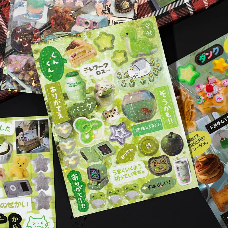A sheet of decorative cut film stickers featuring cute animals and food items on a green background for scrapbooking