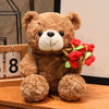A fluffy brown plush bear holding a bouquet of red and green roses.