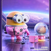 A yellow Minion figure wearing goggles and a pink Minion figure in a clear dome on a purple surface.