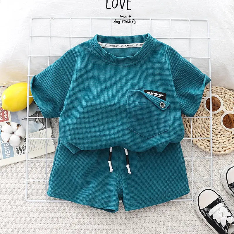 A teal boys' summer cotton t-shirt and shorts set laid out on a white surface.