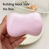 A hand holds a pink squishy fidget block next to a white basket.