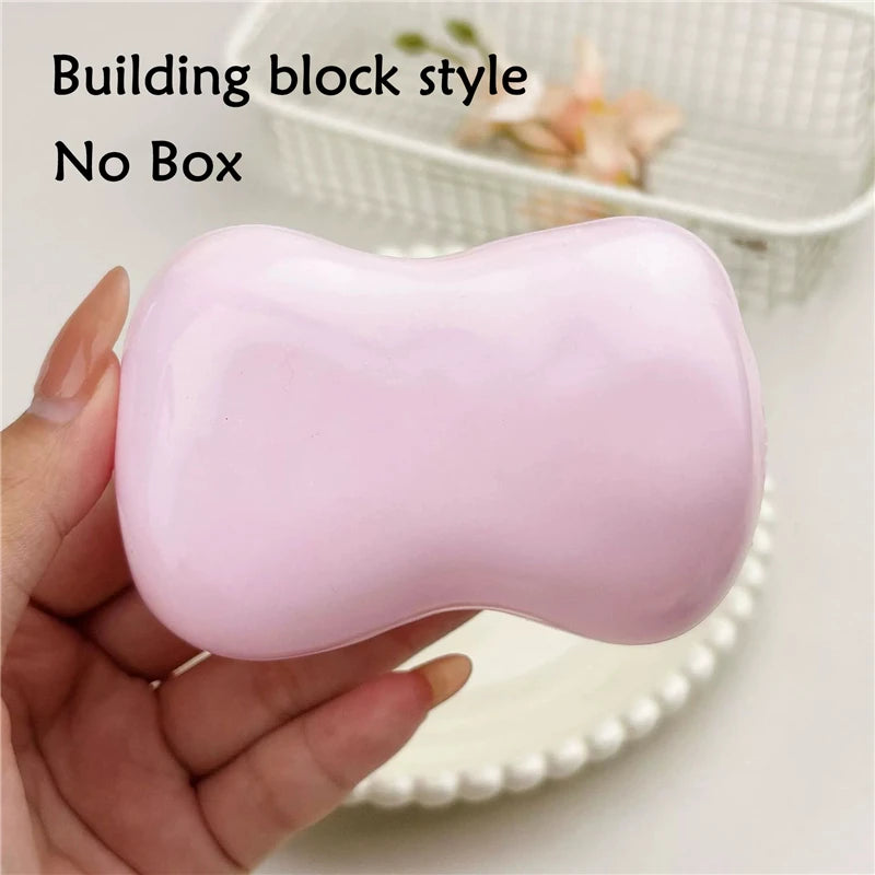A hand holds a pink squishy fidget block next to a white basket.