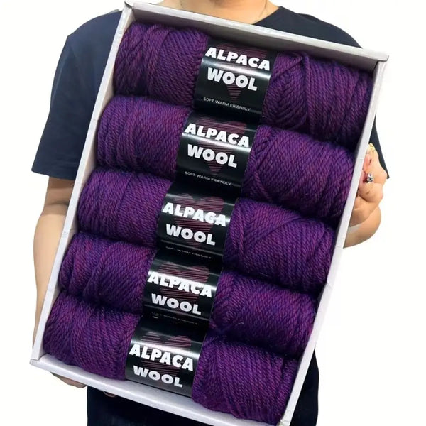 Caja con cinco madejas de lana de alpaca morada para tejer y hacer crochet.