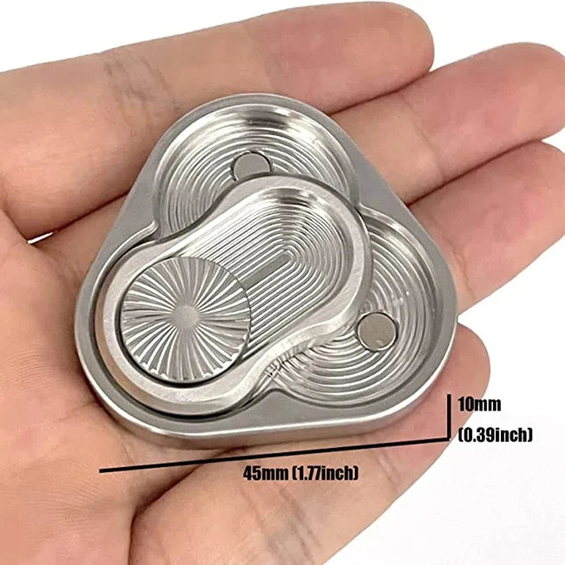 A silver metal magnetic fidget slider with concentric grooves is held in a hand.