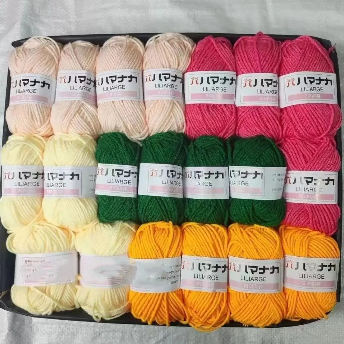 A pack of various colored yarn skeins including pink, green, yellow, and orange wool for knitting and crafts.