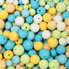 A close-up view of a variety of matte acrylic beads in pastel colors including yellow, blue, green, and white.