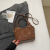 A brown floral canvas tote bag with leather straps is shown next to a gray blazer and a piece of paper.