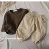 A beige long sleeve cotton tee and matching pants laid out on a white surface.