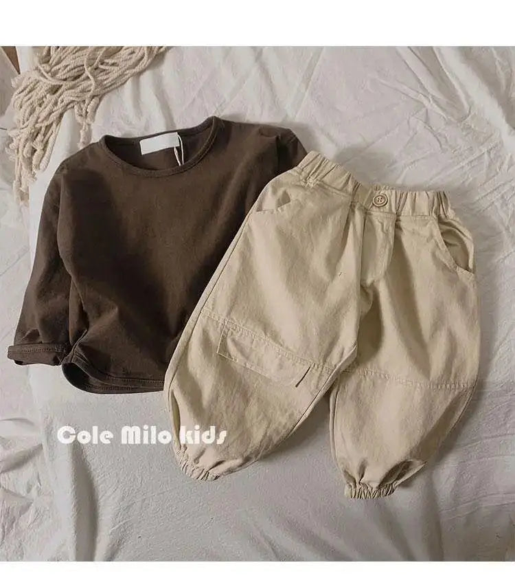 A beige long sleeve cotton tee and matching pants laid out on a white surface.