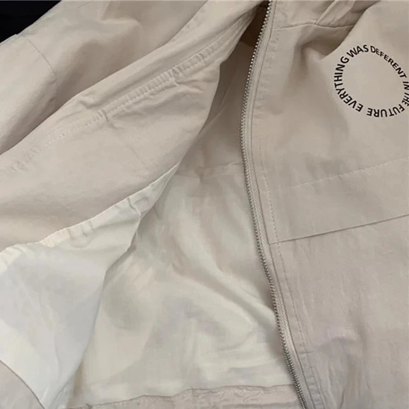 Close-up of a cream-colored kids' hooded letter print zip-up jacket showing the zipper and fabric detail.