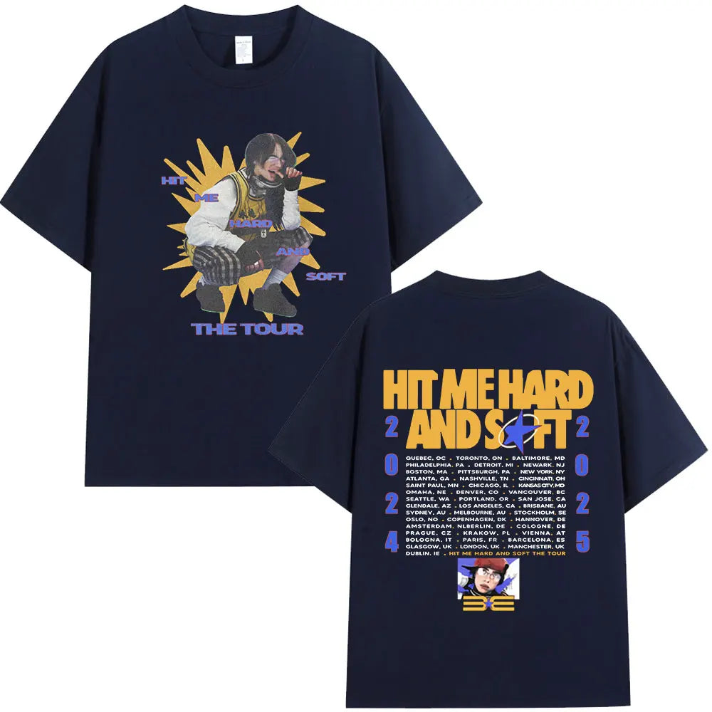 A dark blue t-shirt featuring a graphic of a musician performing on stage with the text HIT ME HARD AND SOFT THE TOUR