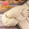 A ball of cream-colored alpaca blend yarn is shown on a wooden surface with a measuring scale and a book.