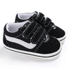 A pair of black and white canvas sneakers with black laces and white soles shown from the side.