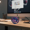 A purple and blue rainbow spinner ring resting on a wooden desk in front of a computer monitor.