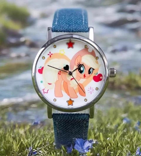 A My Little Pony Magic Sweetheart blind box watch with a pink pony face and blue strap resting on green grass.