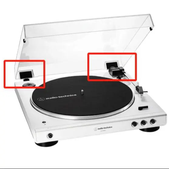 A white audio turntable with its lid open, showing the dust cover hinge mechanism.