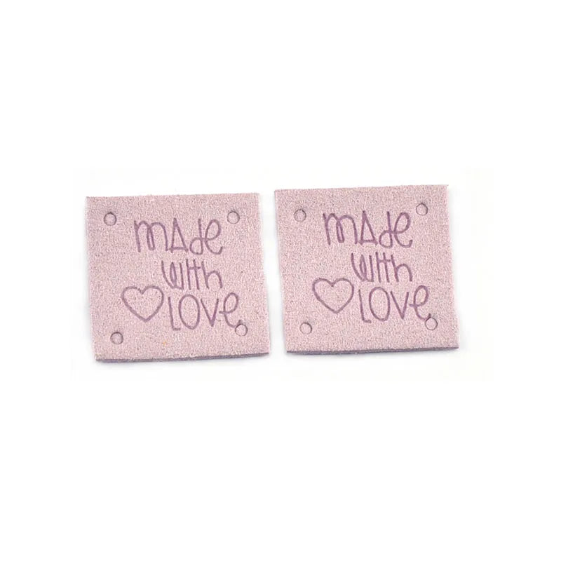 A set of two pink embossed leather labels for sewing and crafts, each reading Made with Love.