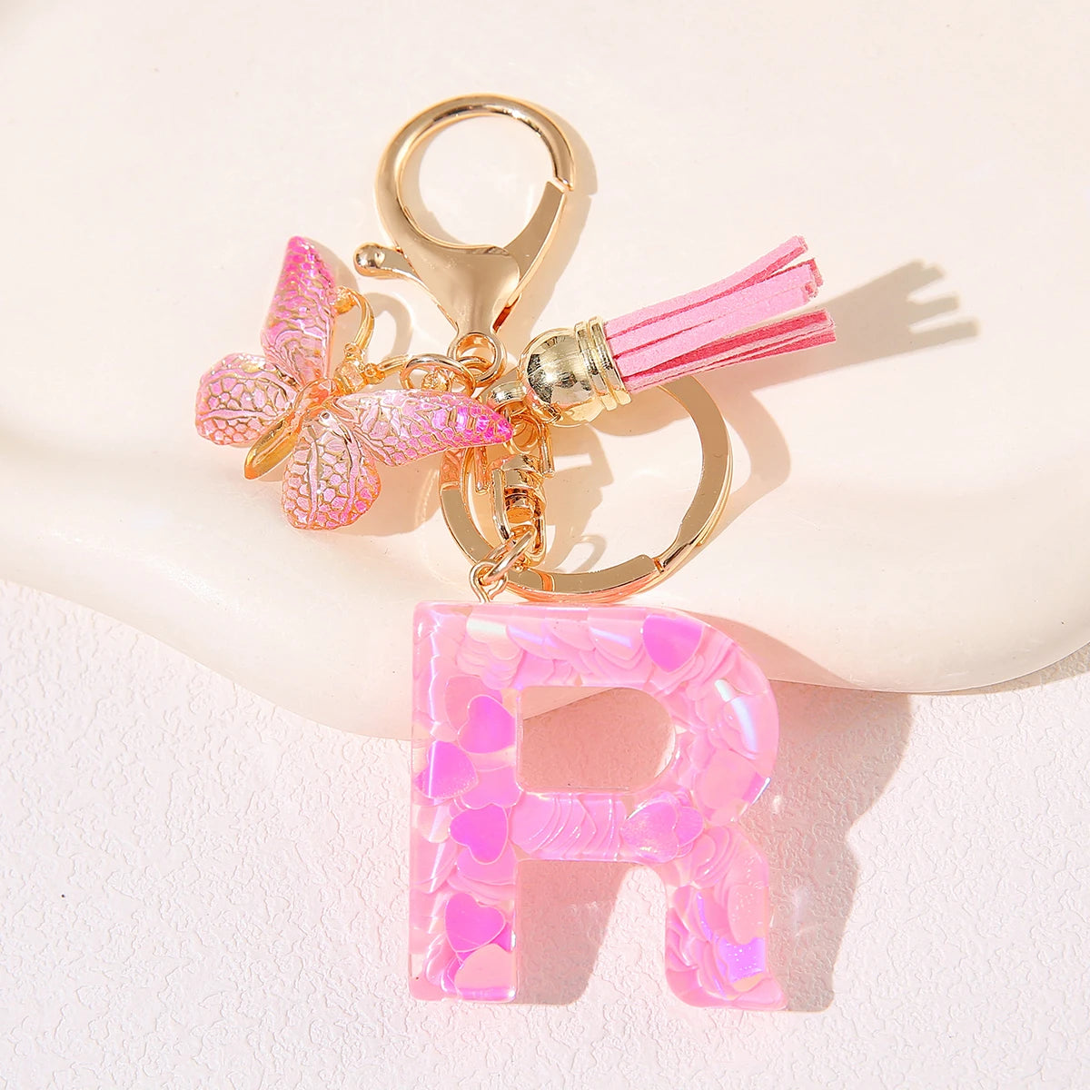 Gold initial heart keychain featuring a pink butterfly charm and a clear pink initial letter.
