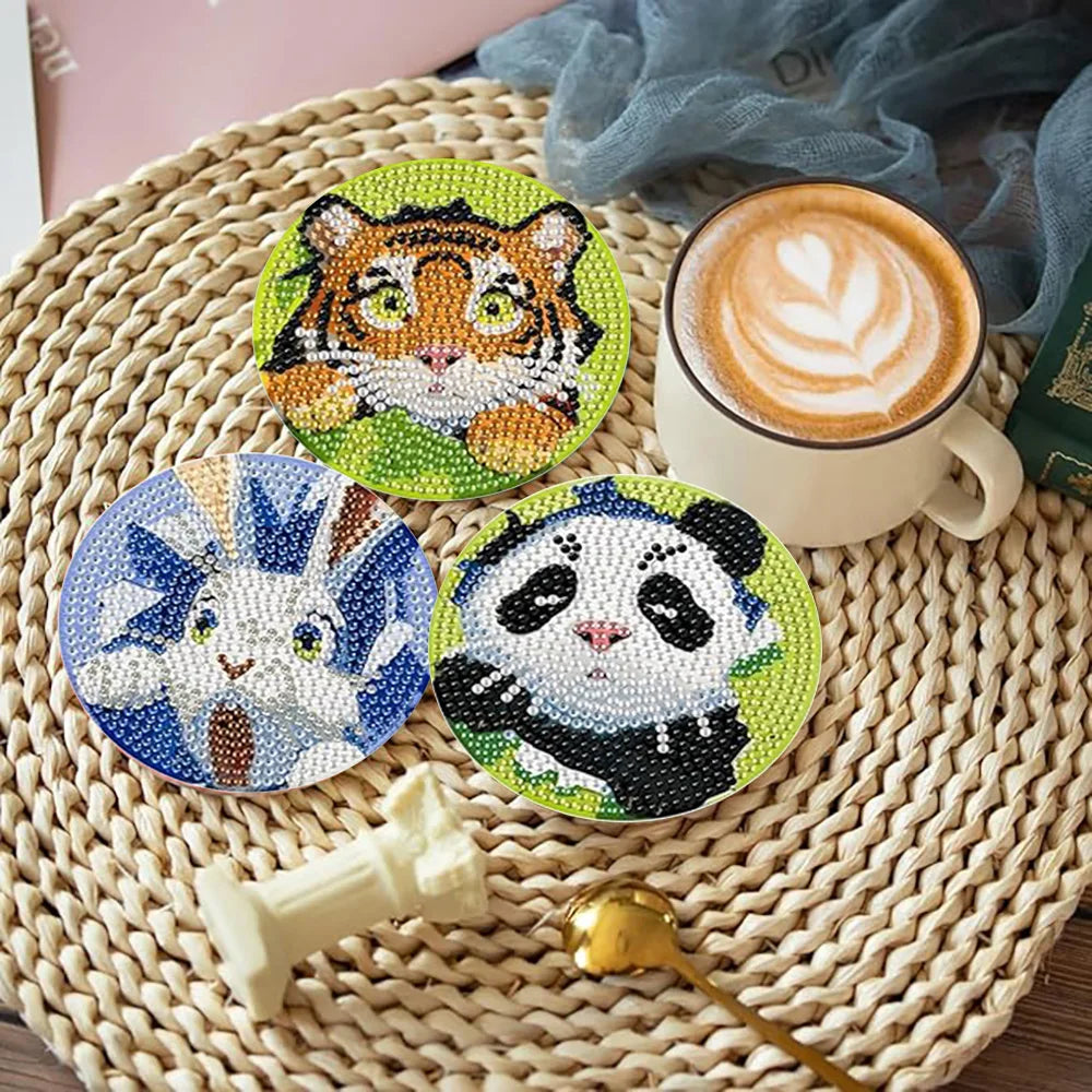 Eight diamond painting coasters featuring tigers and pandas are displayed on a woven mat next to a coffee cup.