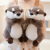 Two brown and white otter plush toys being held by a person.