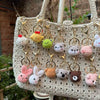 A beige crochet tote bag filled with various animal keychain charms including a rabbit, chick, cat, and dog.