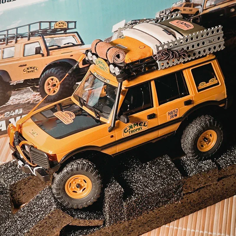 A yellow RC crawler vehicle loaded with a roof bag and bedroll decoration set for display.