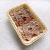 A woven basket filled with five light brown fabric bow baby headbands on a white textured surface.