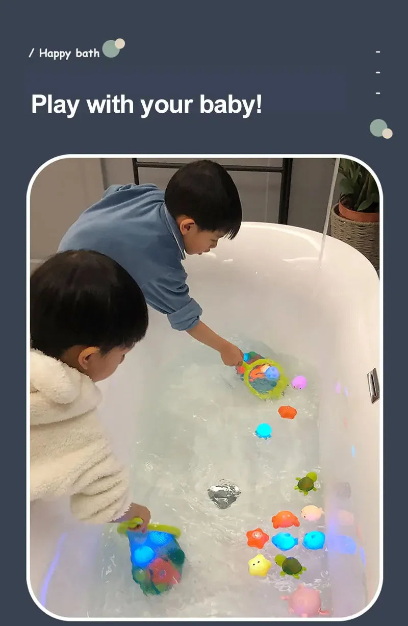 A baby is playing with a colorful LED light-up bath toy set in a white bathtub filled with water.