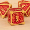 A close-up of a red and gold metal dice set for Dungeons & Dragons, featuring polyhedral dice.