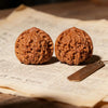 Two hand-polished brown walnuts resting on aged paper.