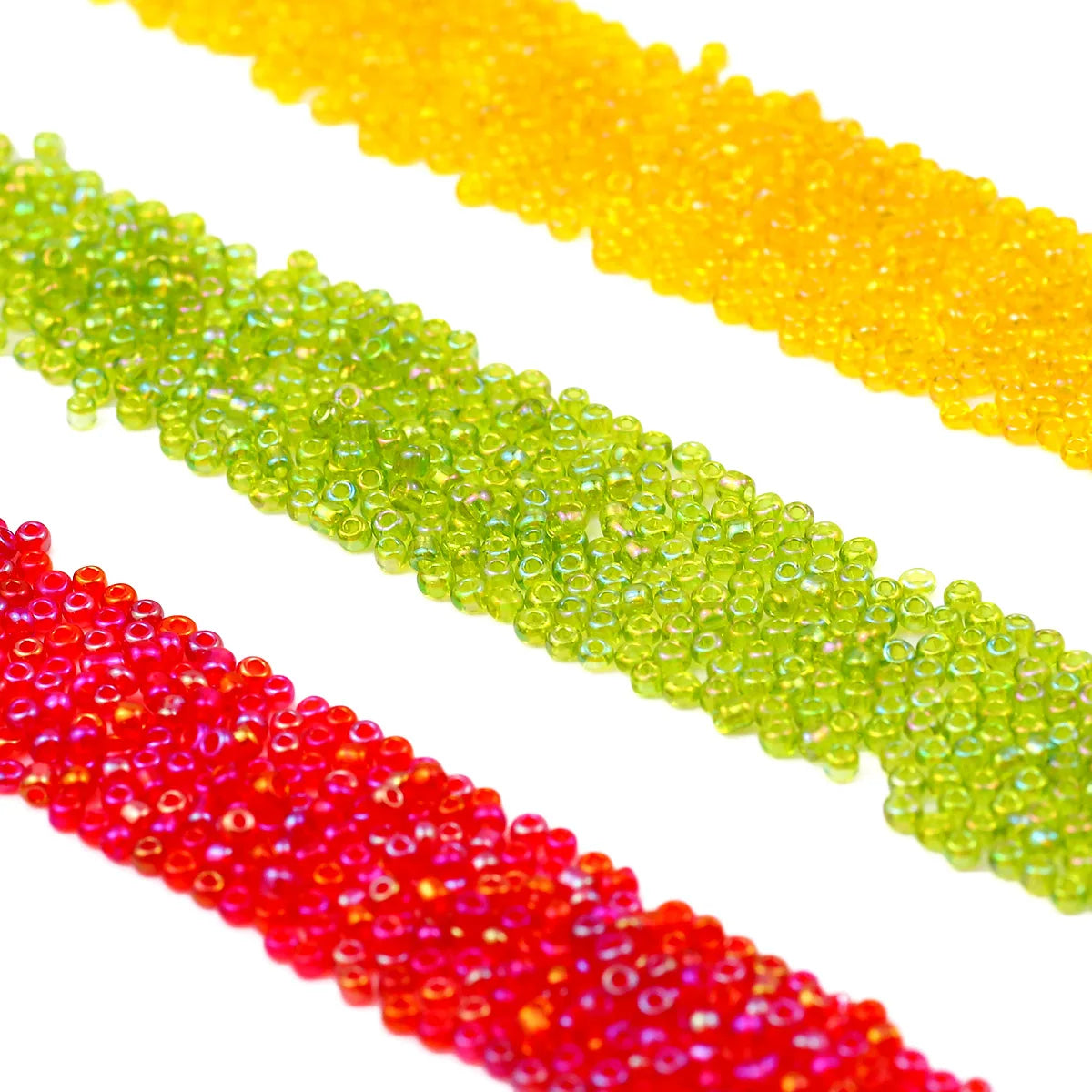 A close-up view of various strands of glossy glass seed beads in yellow, green, and red.