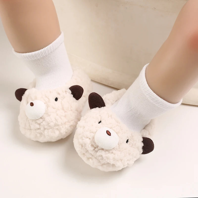 Pair of adorable cartoon baby booties resembling white sheep with black accents and white socks