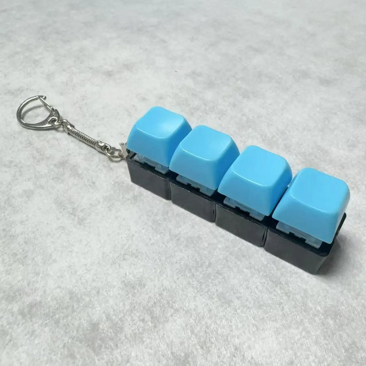 A set of four light blue acrylic key buttons attached to a silver chain keychain.