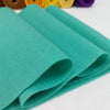 A stack of teal felt fabric sheets folded neatly on a white surface.