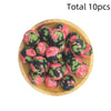 A wooden bowl filled with ten pink and green floral printed silicone beads for DIY jewelry making
