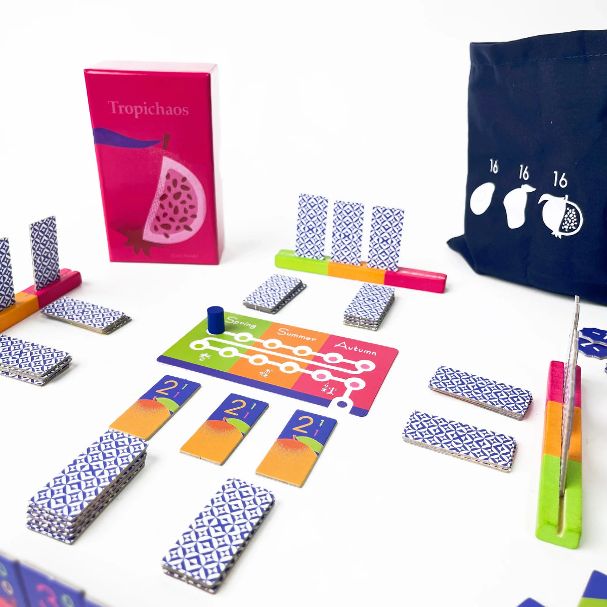 A collection of colorful wooden tiles and a dark blue bag for a variety board game set.
