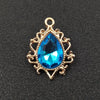 Gold plated water droplet charm featuring a brilliant blue crystal rhinestone set in an ornate flower design.